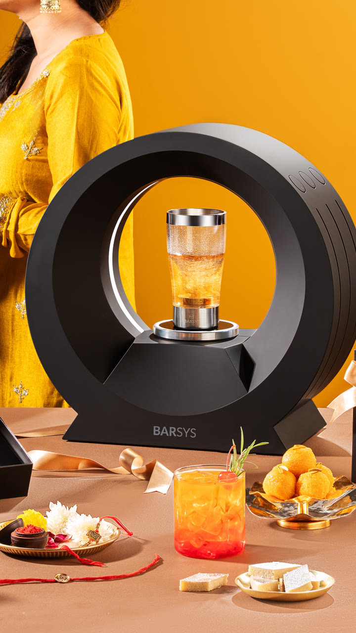 A Barsys 360 on a table of drinks and snacks, a guest reaching for the glass.