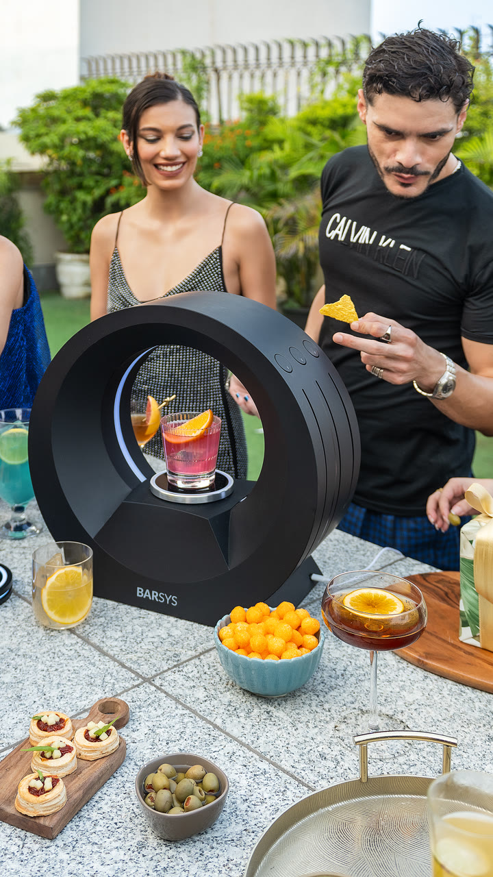 Two guests beside a Barsys 360 on an outdoor terrace table.
