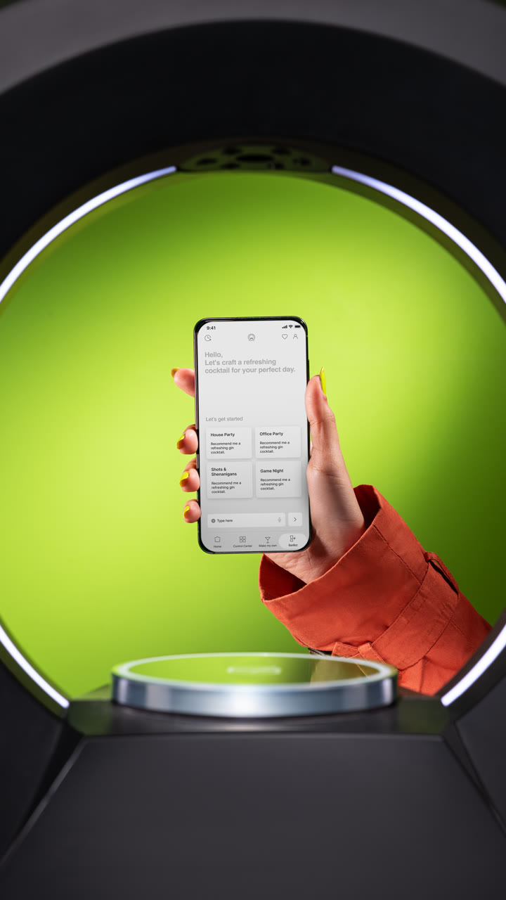 A hand holds the Barsys app inside the lit ring of a green-lit 360.